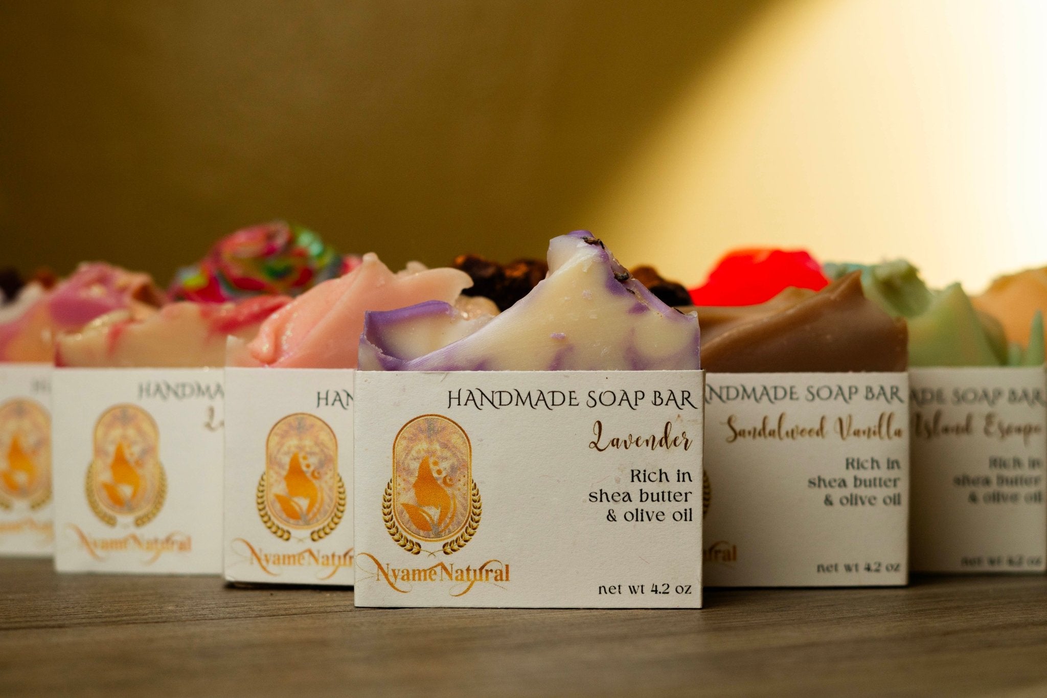 Colorful handmade soap bars with labels, showcasing luxurious body soap rich in shea butter and olive oil.