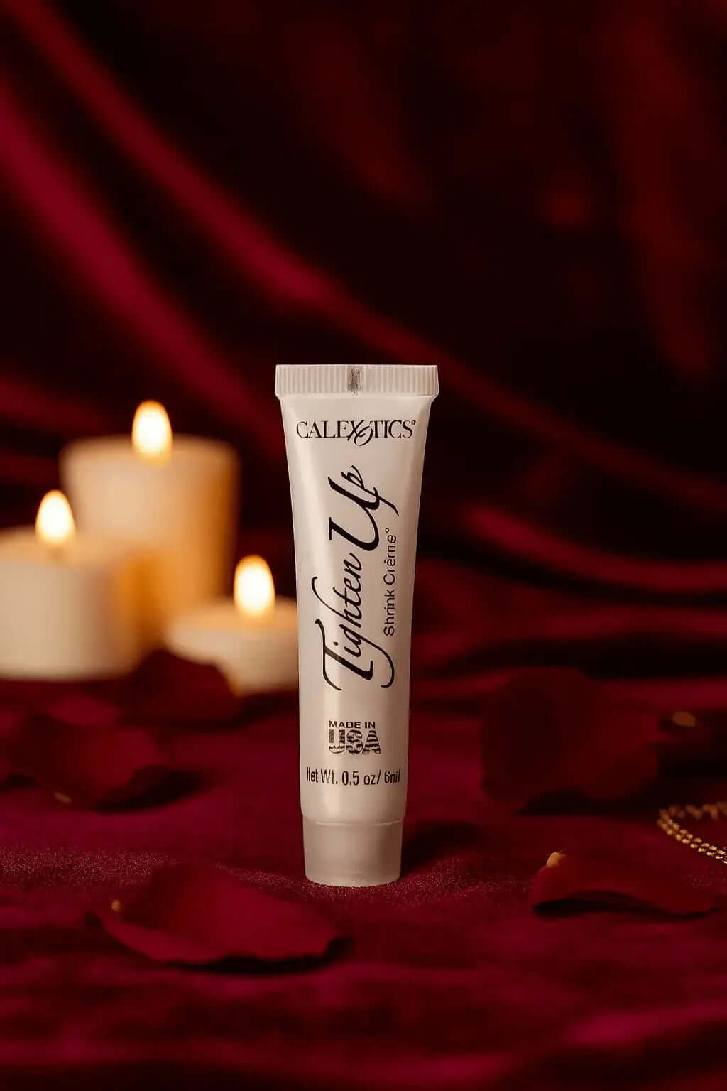 CalExotics Tighten Up vaginal tightening cream tube on red velvet with candles and rose petals