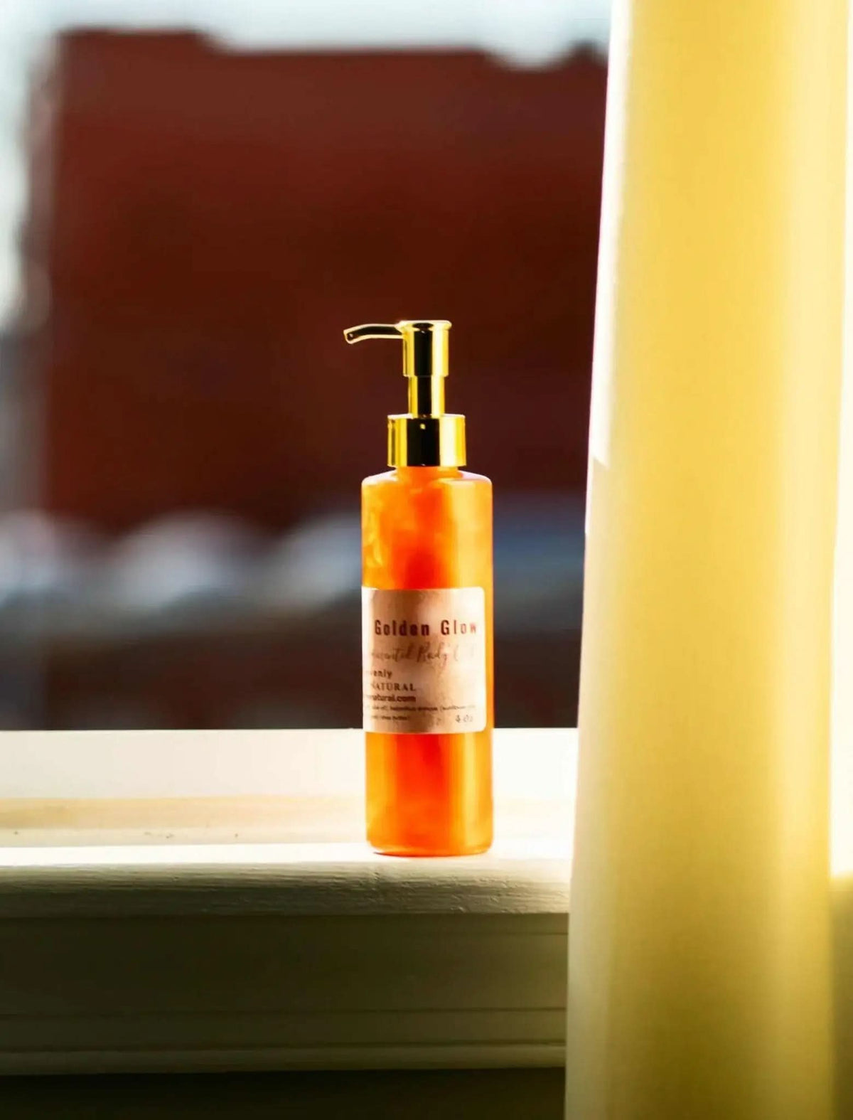 RoyalLuxsLLC copper body oil in a golden pump bottle placed on a windowsill with soft natural light