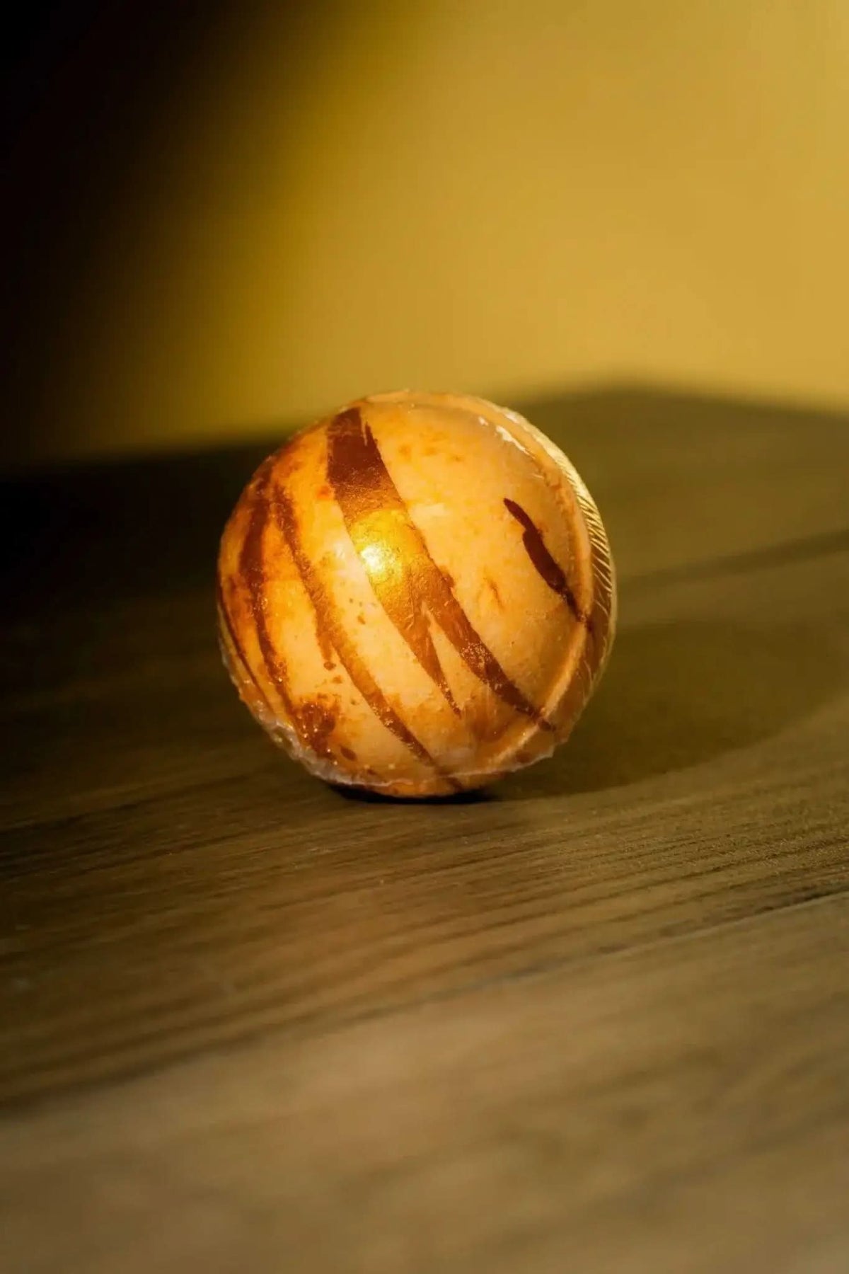 RoyalLuxsLLC luxurious herbal bath bomb with natural brown stripes on wooden surface