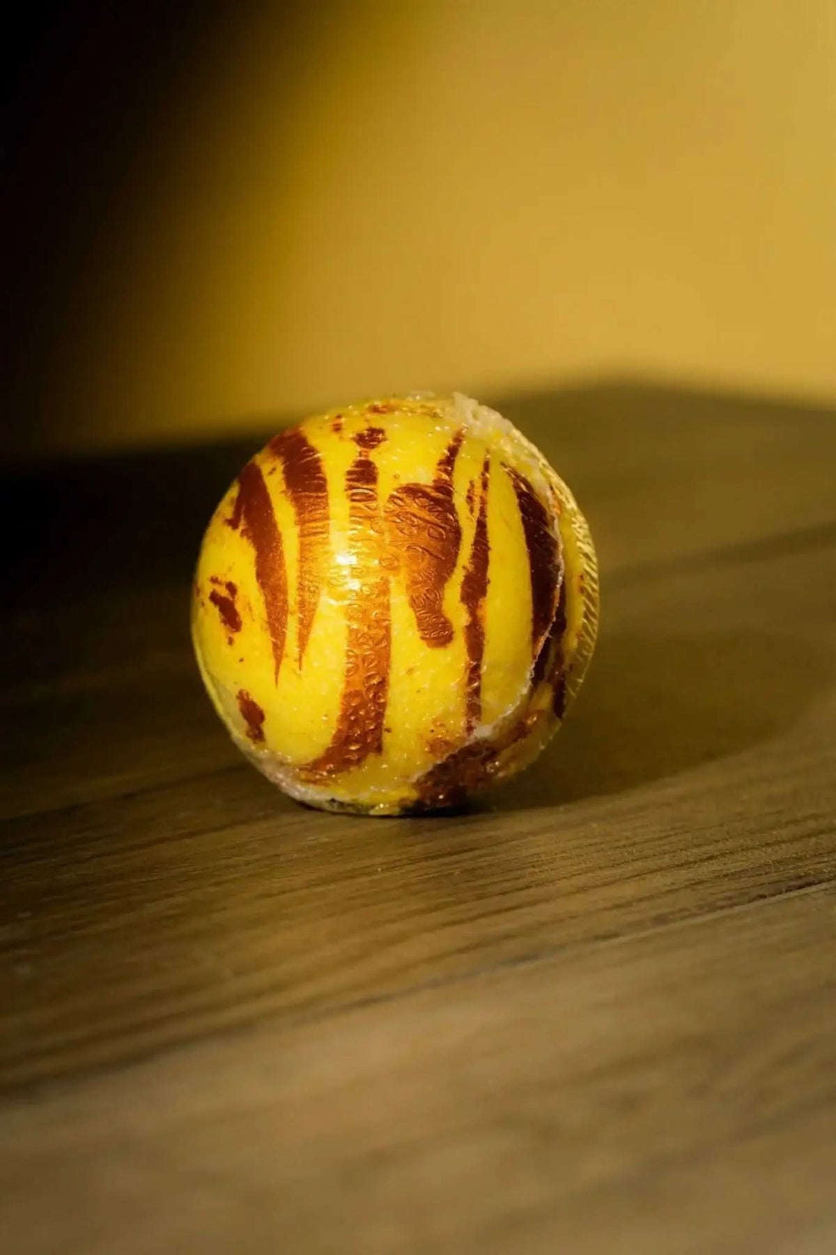 Luxurious herbal bath bomb with yellow and brown swirls by RoyalLuxsLLC on wooden surface