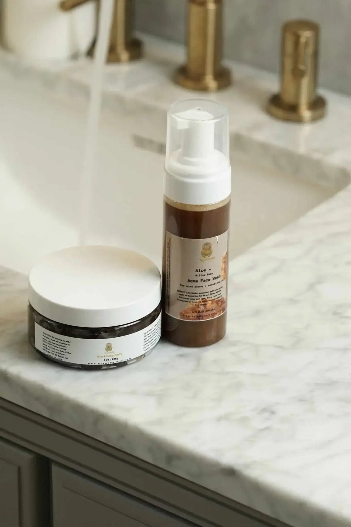 RoyalLuxsLLC natural acne face wash for sensitive skin bottle and cream jar on marble bathroom counter