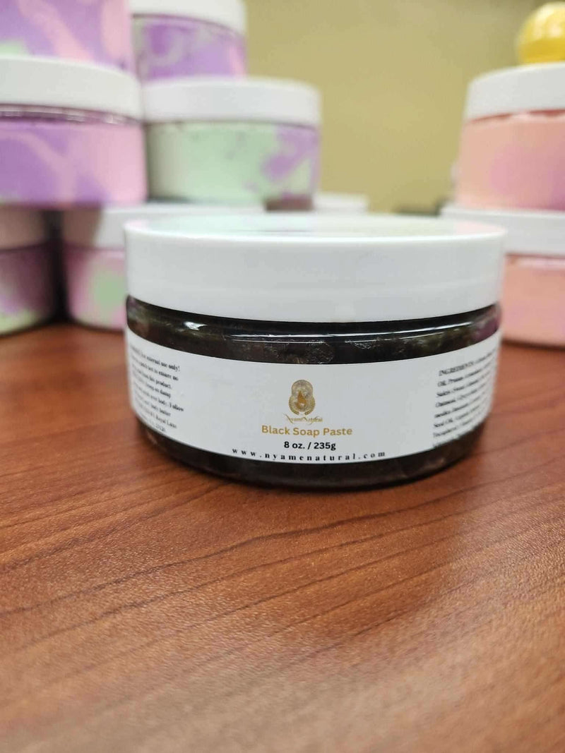 RoyalLuxsLLC African black soap paste for face in a white-lid jar on wooden surface