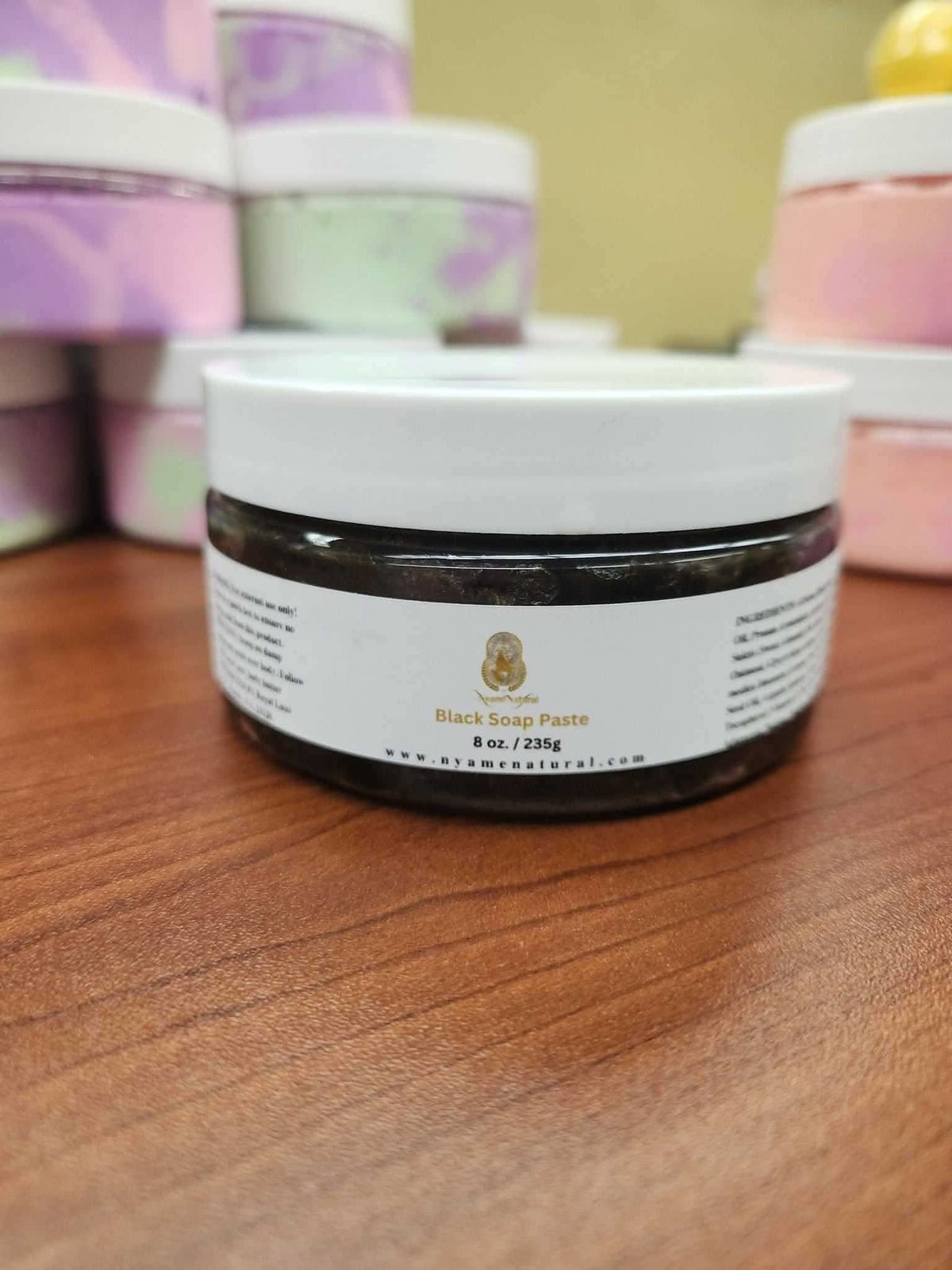 RoyalLuxsLLC African black soap paste in a round jar with white lid on wooden surface
