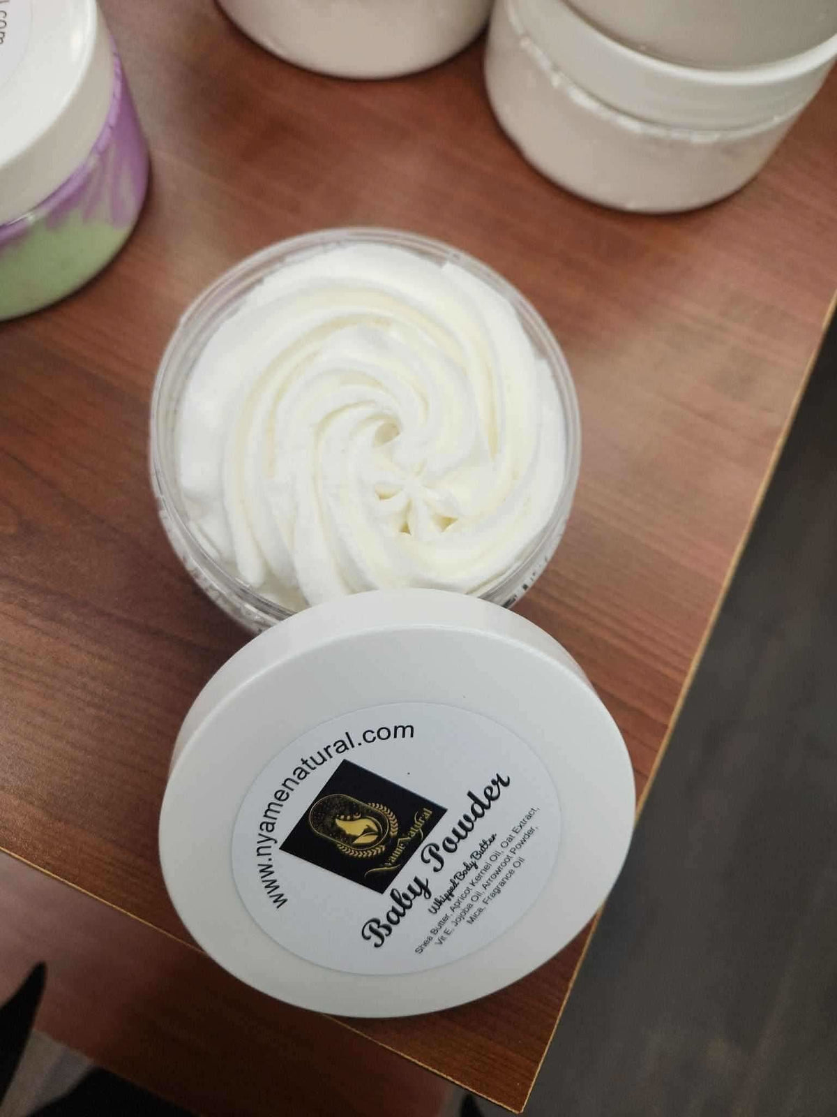RoyalLuxsLLC baby powder body butter in a clear jar with whipped creamy texture on wooden surface