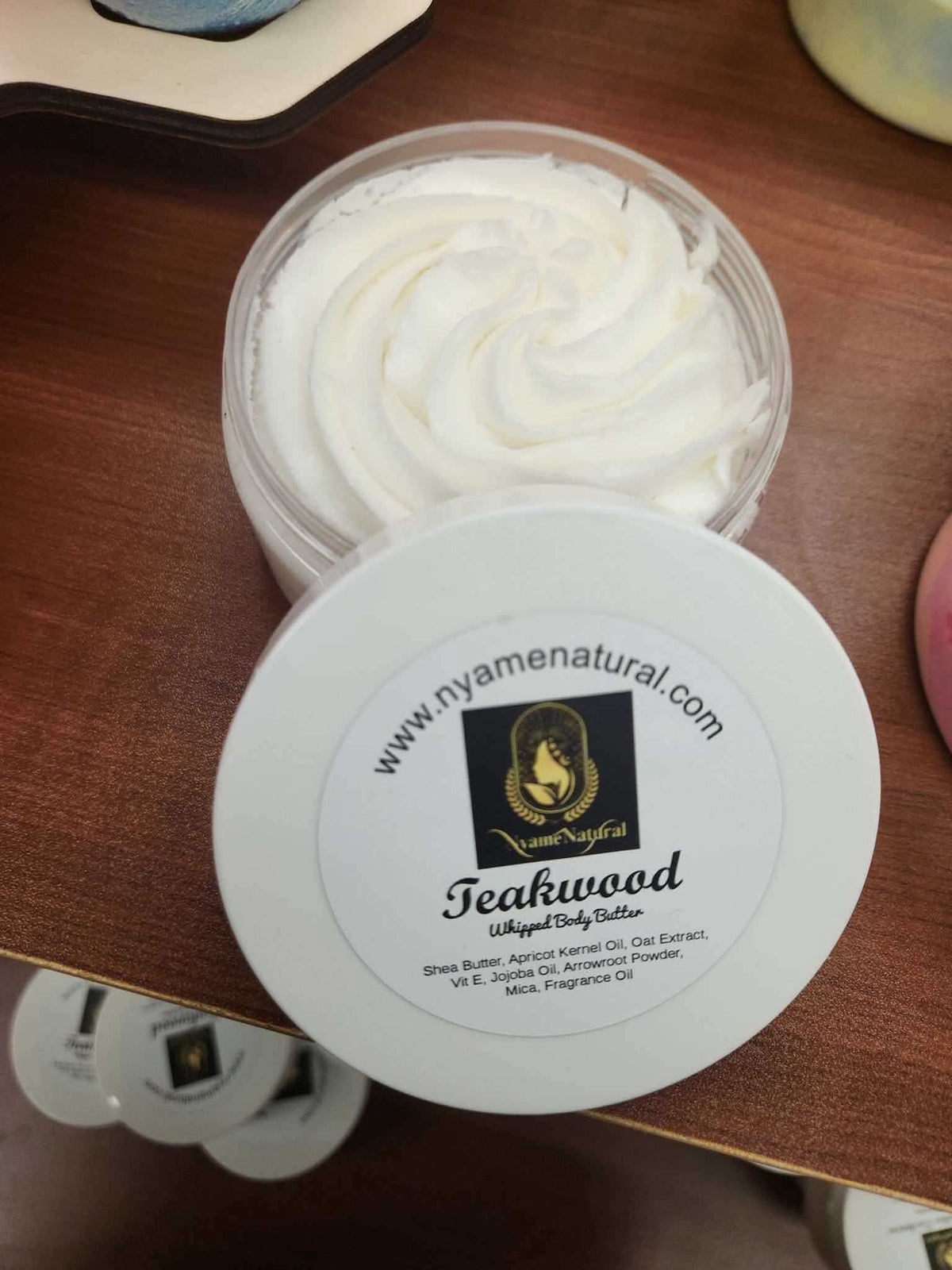 Open jar of teakwood body butter by RoyalLuxsLLC showing creamy white texture on wooden surface