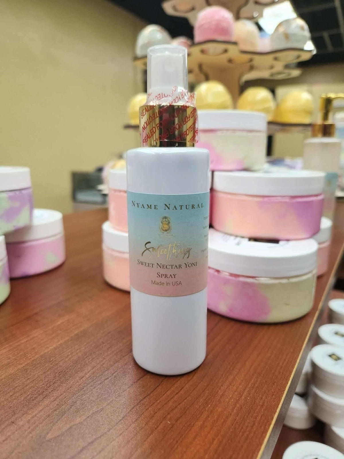 RoyalLuxsLLC natural yoni spray bottle on wooden surface with skincare jars in background