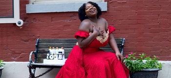 Woman in red dress sitting on bench with best herbal health products like shampoos and body butter displayed