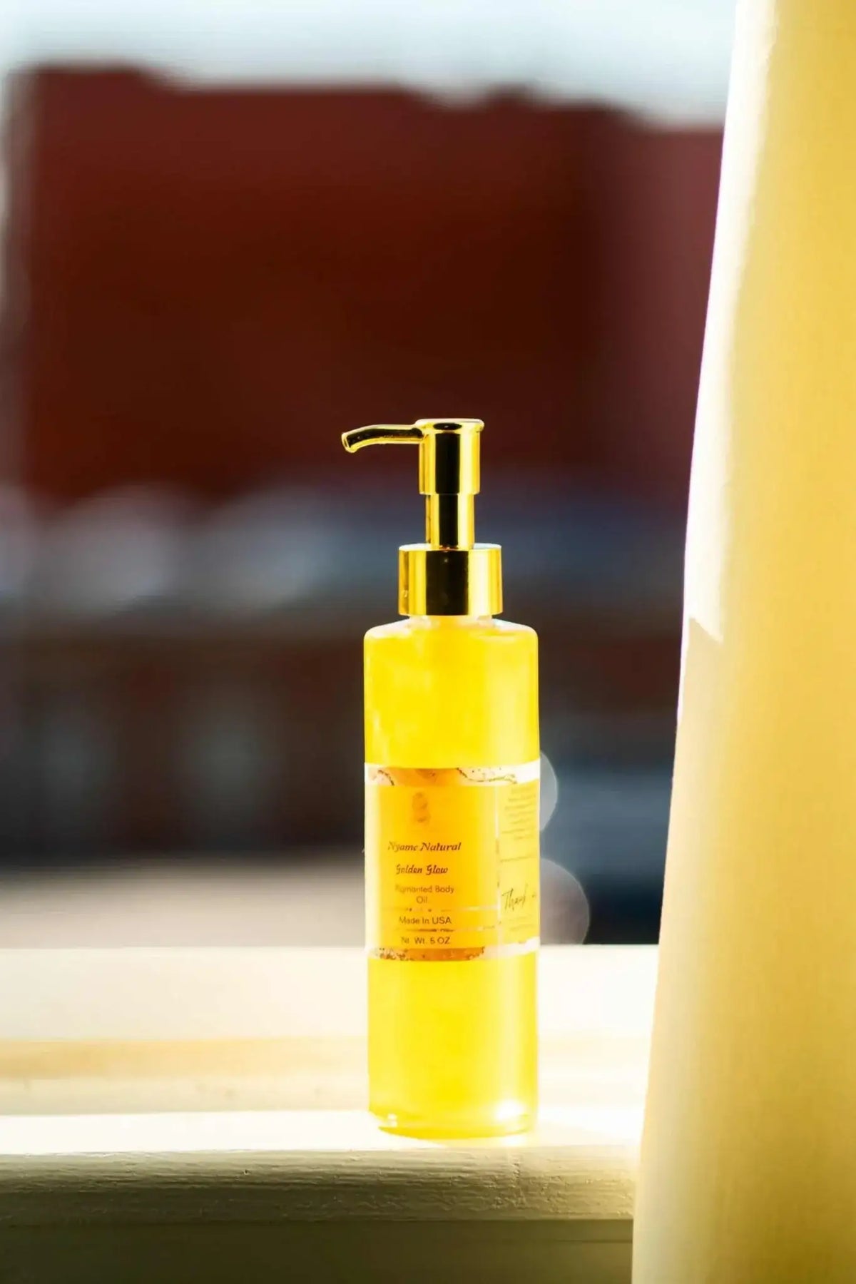 24k Gold Pigmented body oil in a sleek bottle, showcasing its radiant glow for skin moisturization and fragrance.