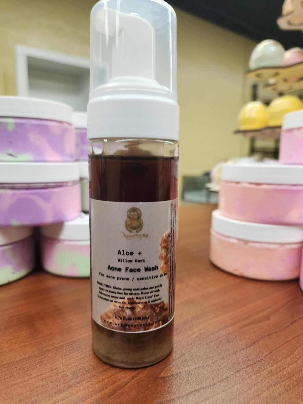 Aloe & willow Bark Acne Face Wash for Sensitive Skin in a bottle with foam pump on a wooden table.