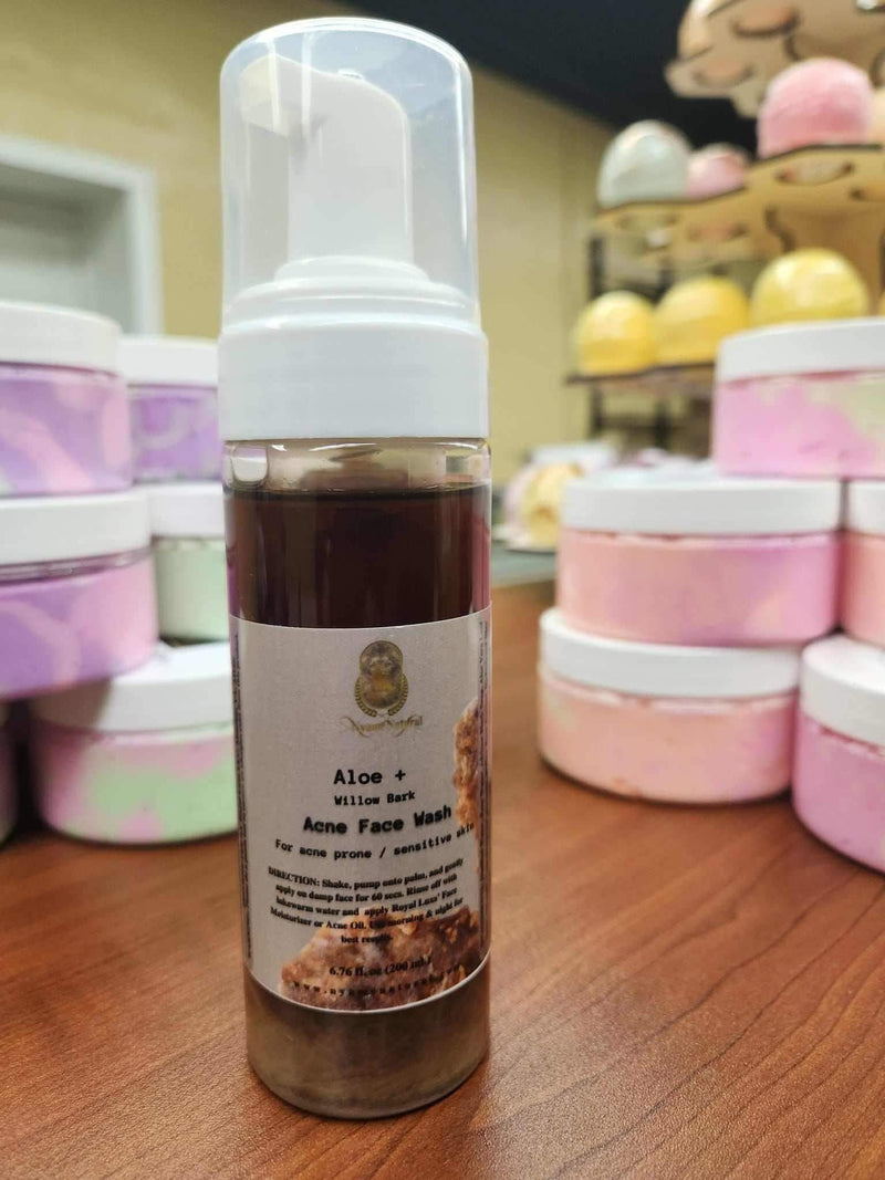 Aloe & willow Bark Acne Face Wash for Sensitive Skin displayed on a wooden table with colorful skincare products.