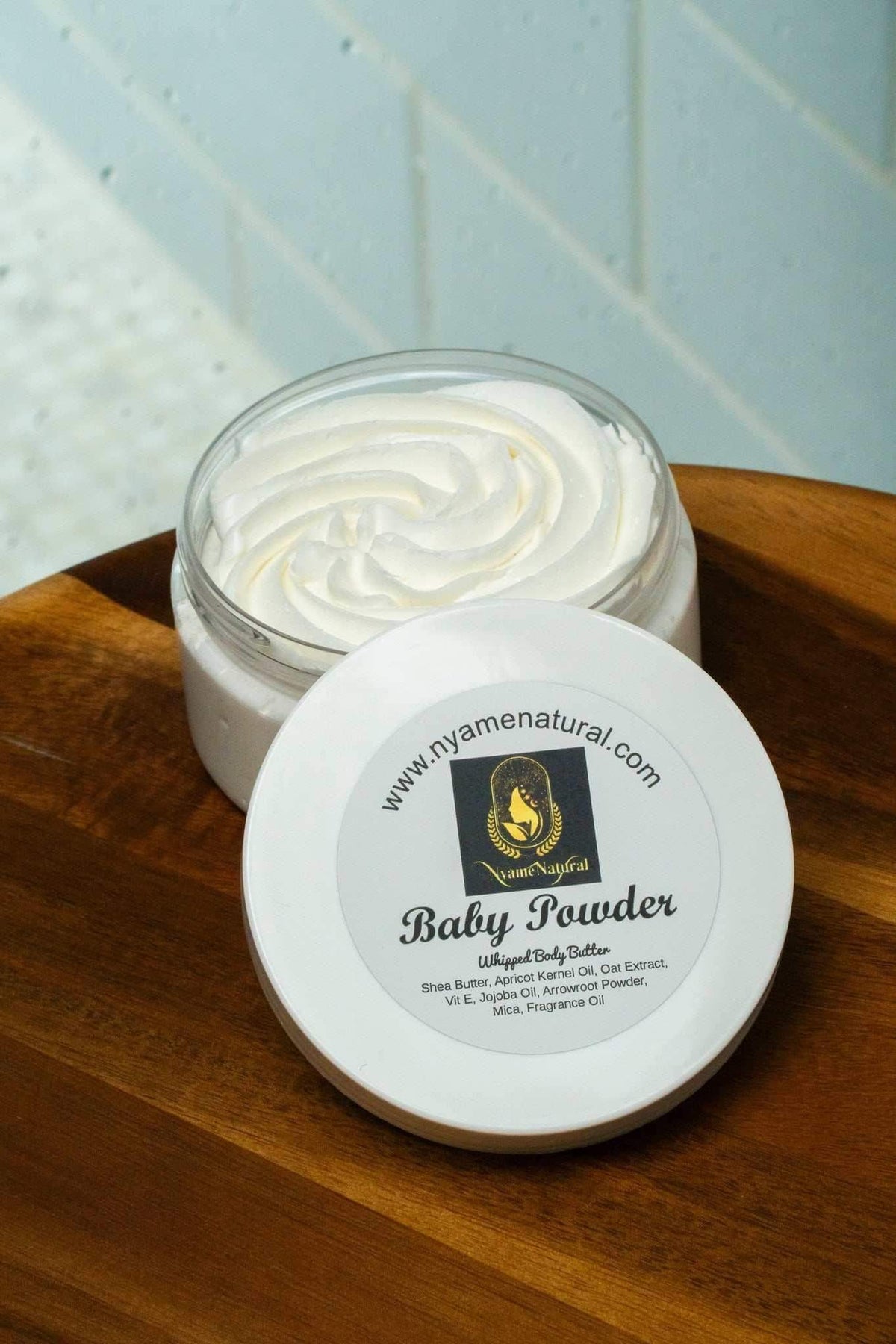 Baby Powder Body Butter in a jar on wooden surface, perfect for hydration and skin nourishment.