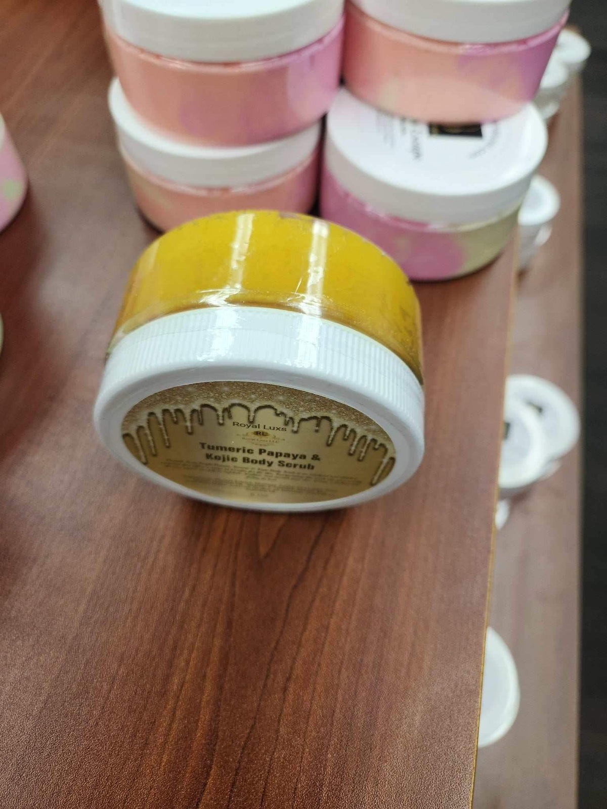Bright Turmeric' Papaya & Niacinamide Body scrub in a yellow jar on display, promoting skin rejuvenation.