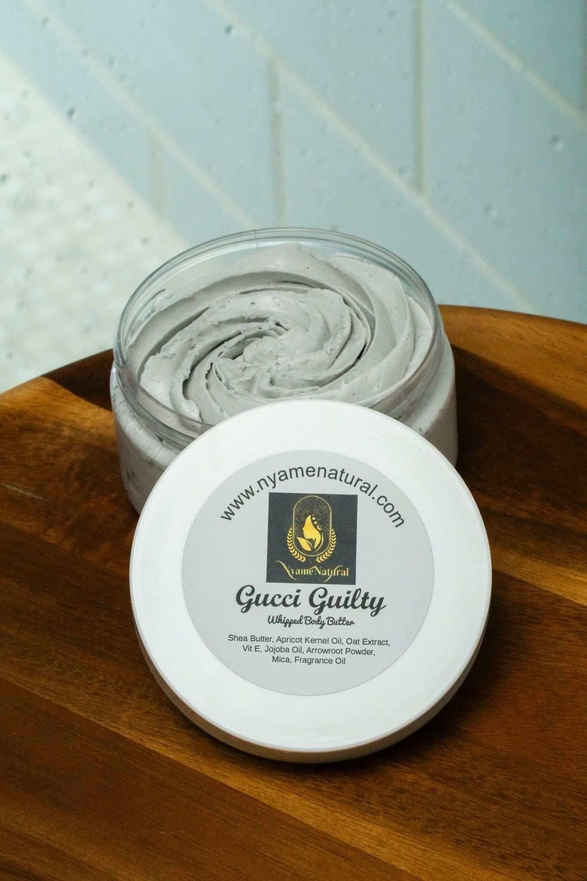 Open jar of Gucci Guilty body butter by RoyalLuxsLLC with creamy texture on wooden surface