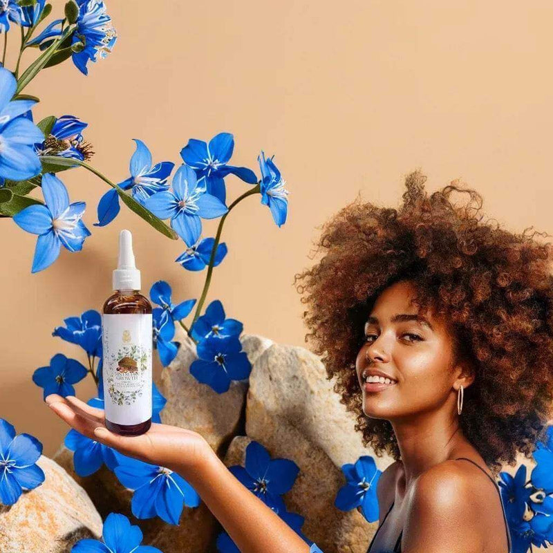 3 in 1 Supergrowth Batana Chebe Haitian Black Castor Oil held by a woman surrounded by vibrant blue flowers.