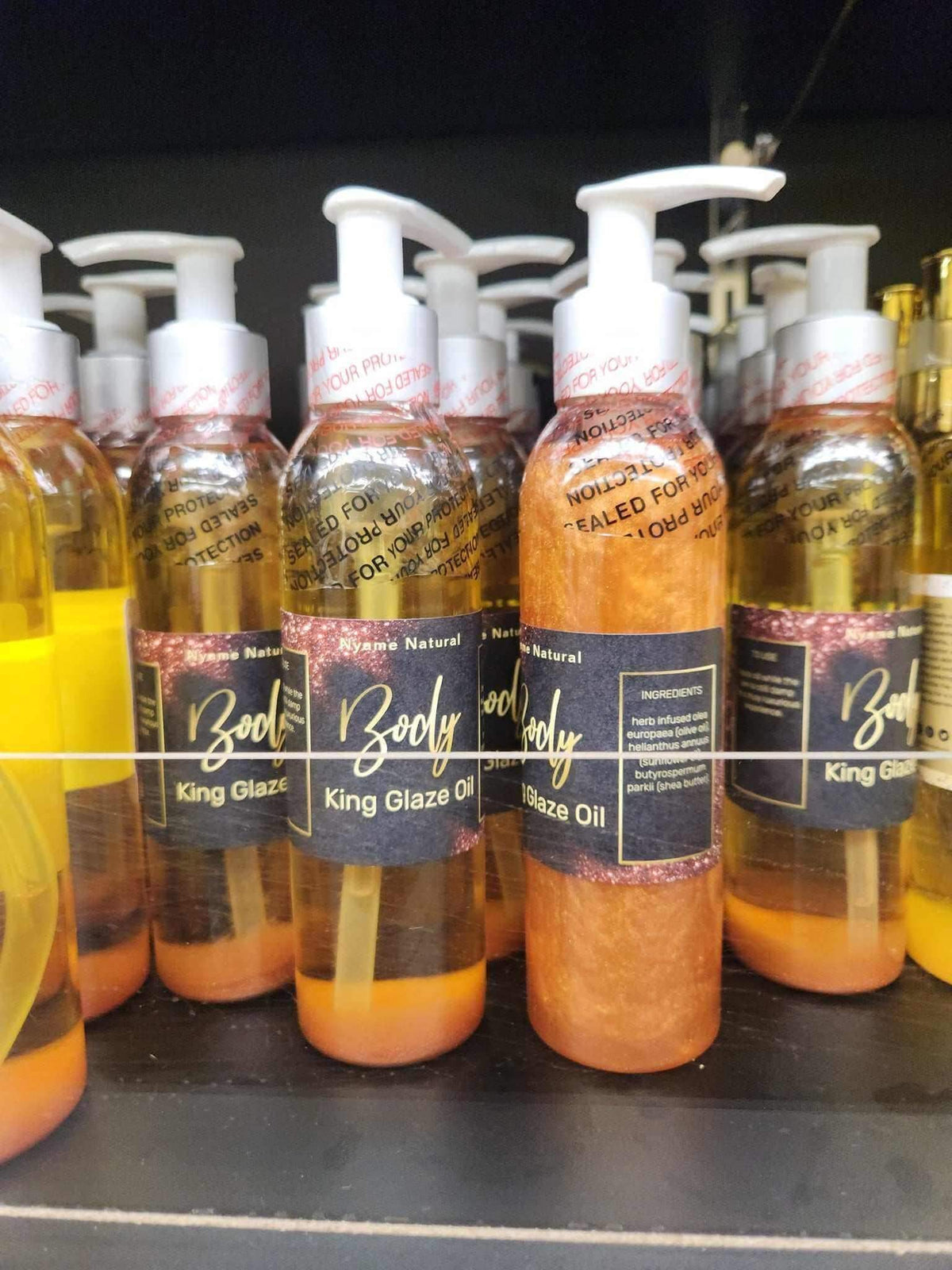 King Glaze Body oil bottles lined up on a shelf, showcasing luxurious herbal tonic with black seed and detox benefits.