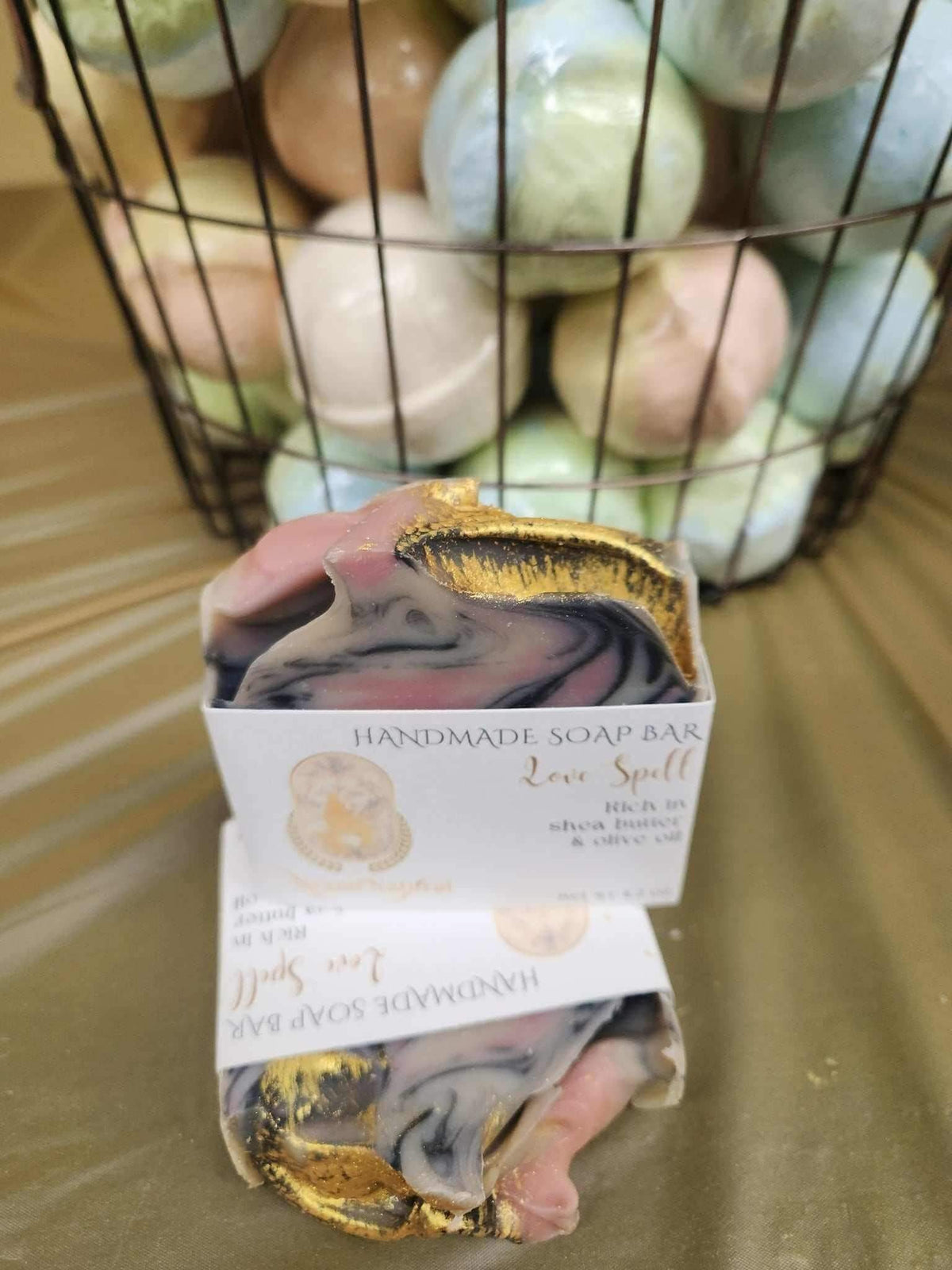 Love Spell Bar Soap wrapped in elegant packaging next to colorful bath bombs, creating a serene cleansing experience.