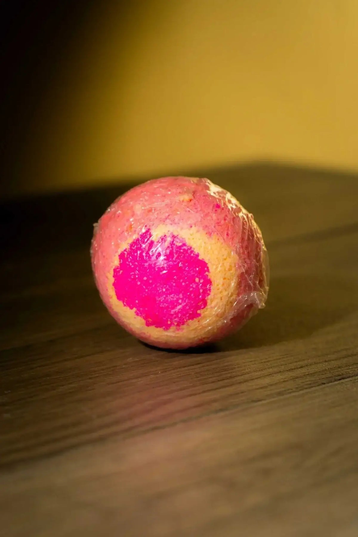 Luxurious Body Bath Bomb with vibrant colors and unique fragrances on a wooden surface.