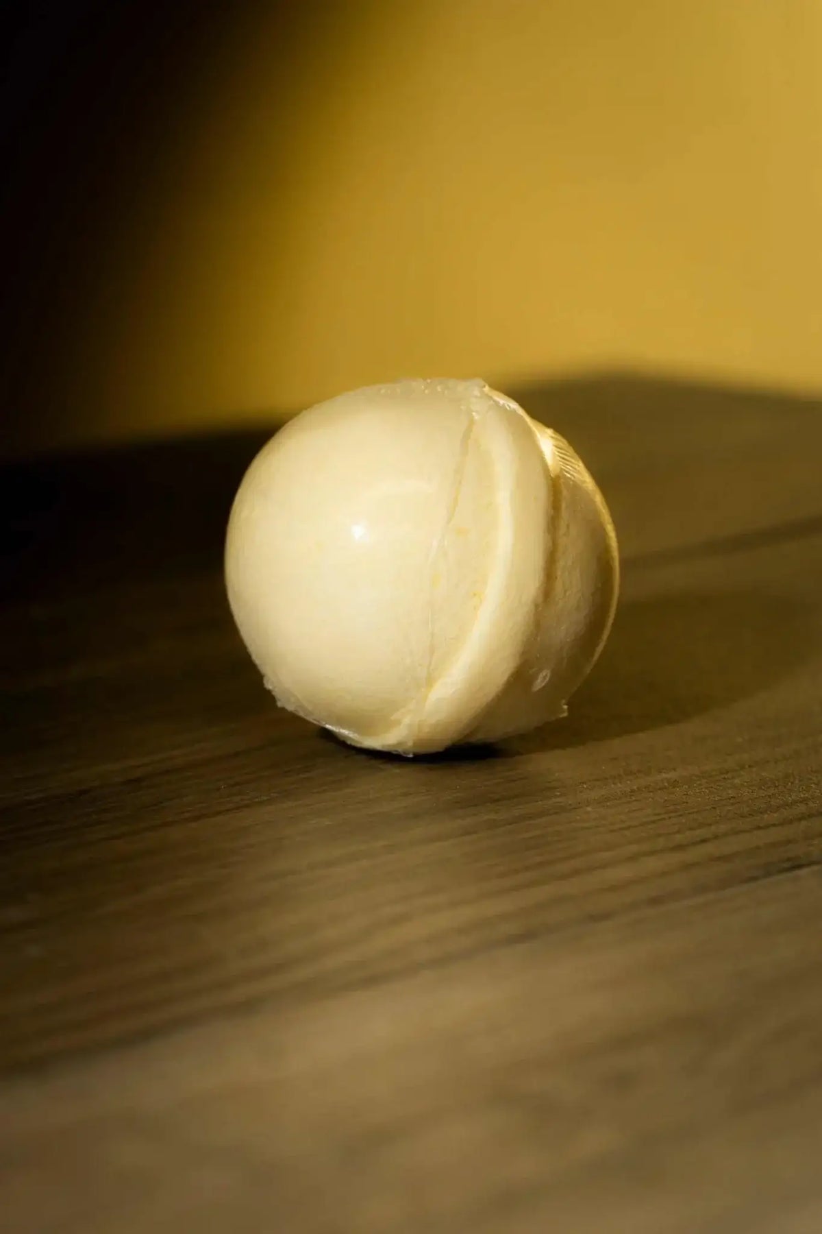 Luxurious Body Bath Bomb on wooden surface, handcrafted with skin-loving ingredients for a rejuvenating soak.