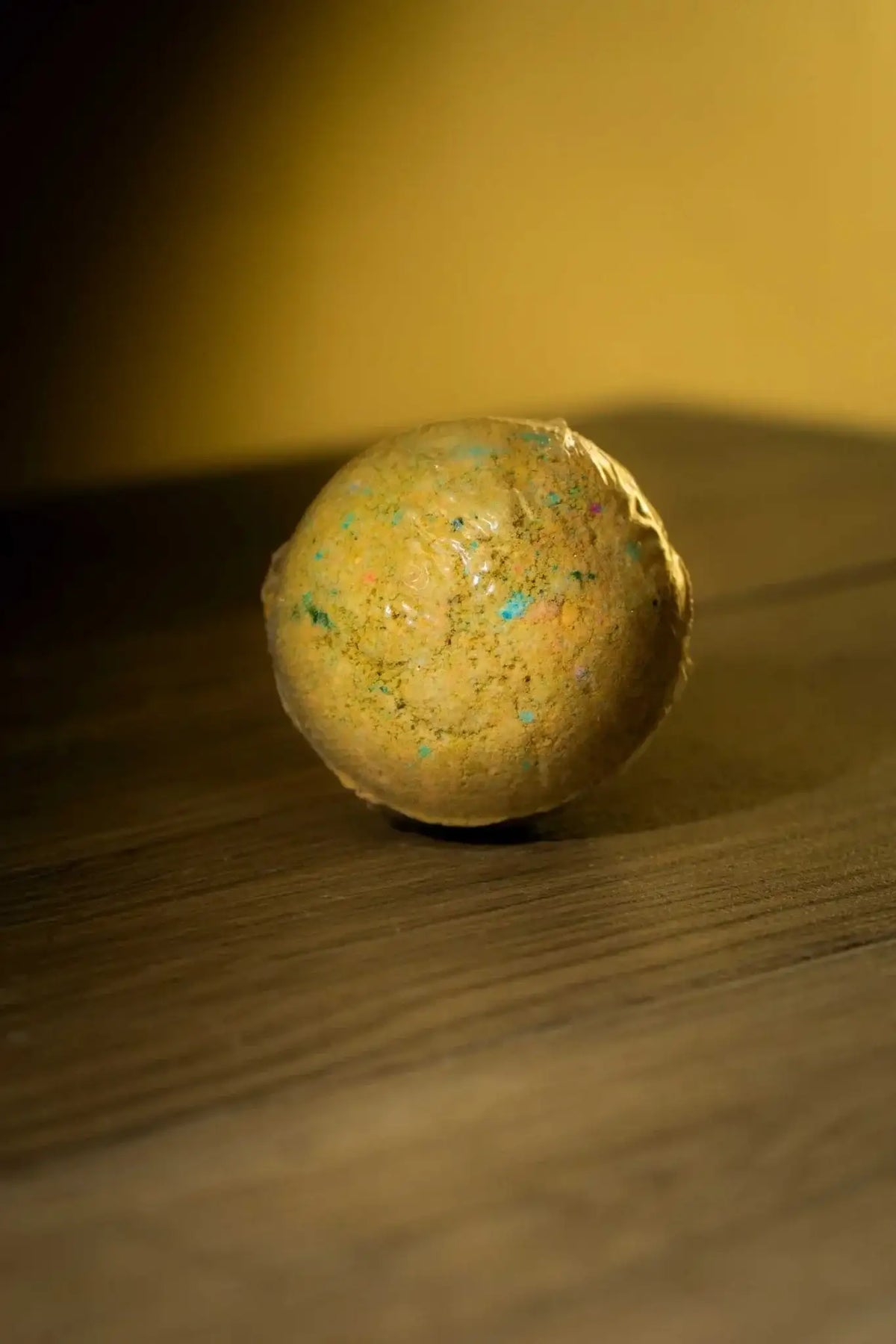 Luxurious Body Bath Bomb with vibrant colors on a wooden surface, perfect for detox and cleanse.