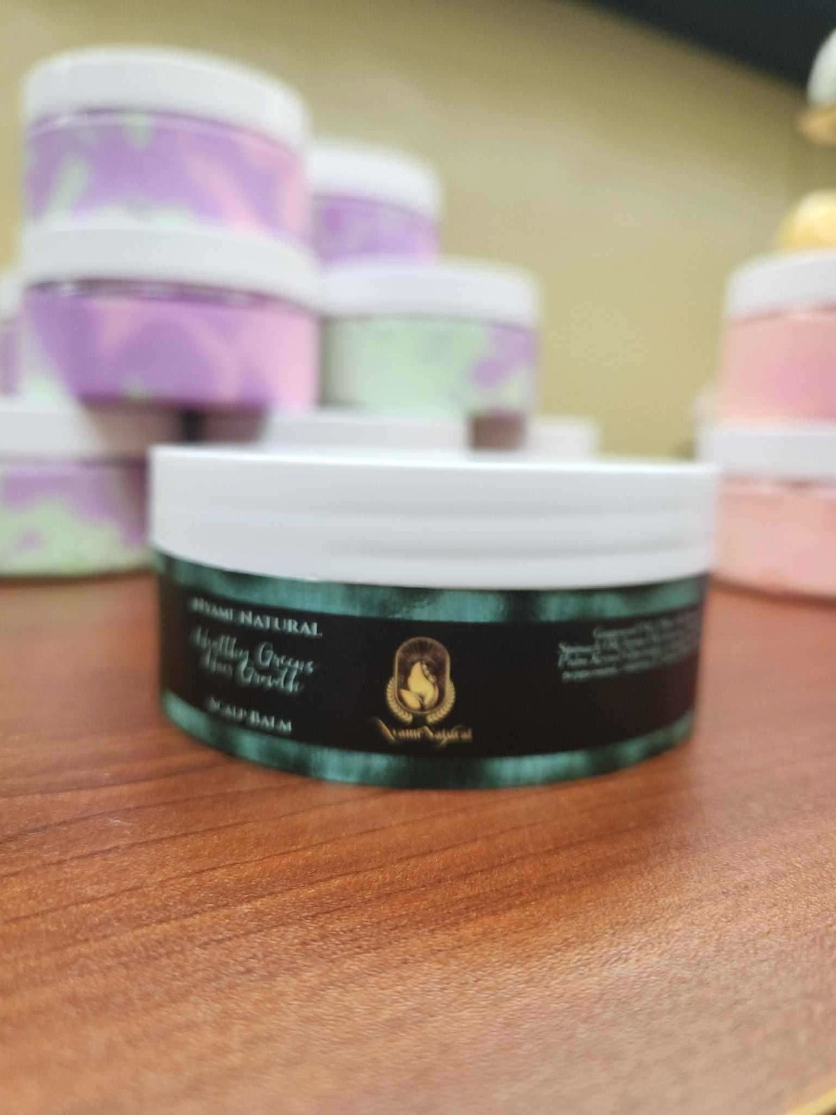 RoyalLuxsLLC herbal scalp balm for healthy hair in a round container on a wooden surface