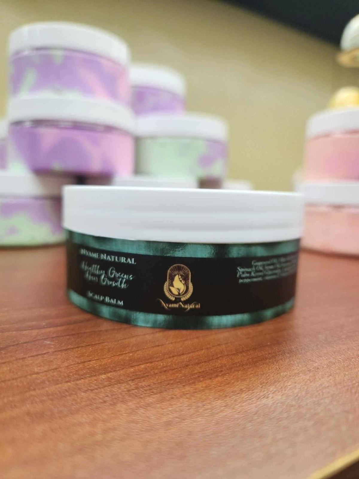 RoyalLuxsLLC herbal scalp balm for healthy hair in a green and black jar on wooden surface