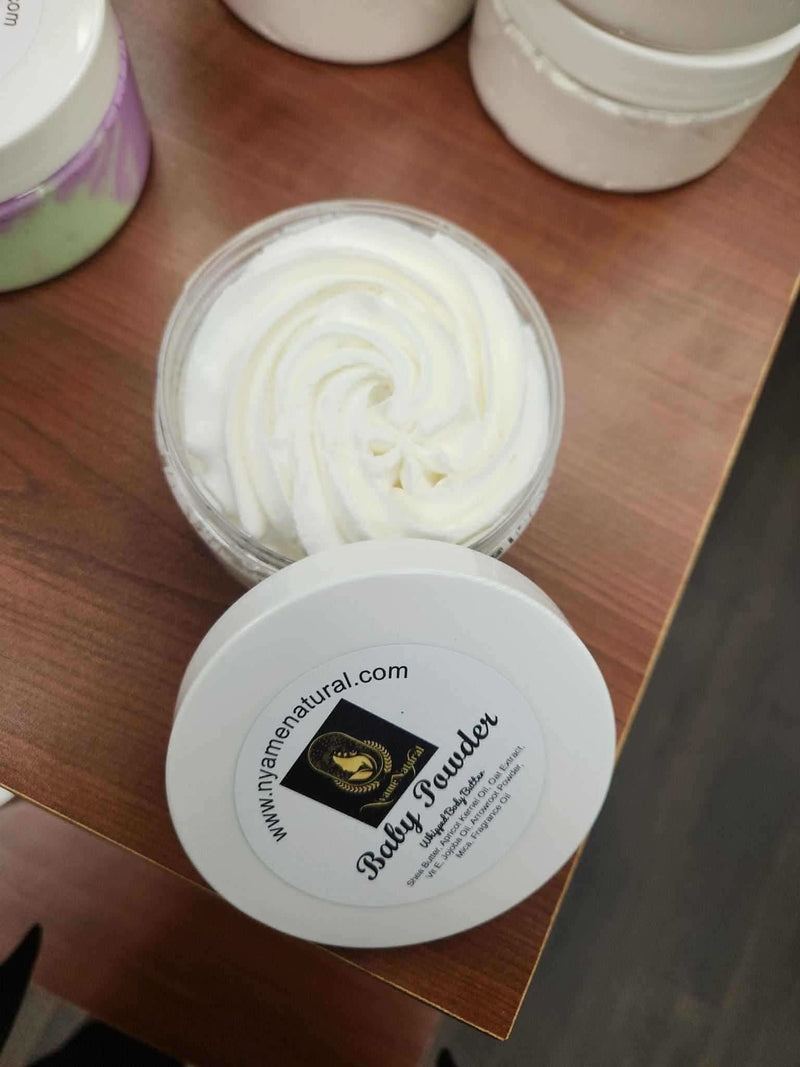 RoyalLuxsLLC baby powder body butter in a white jar with whipped texture on wooden surface