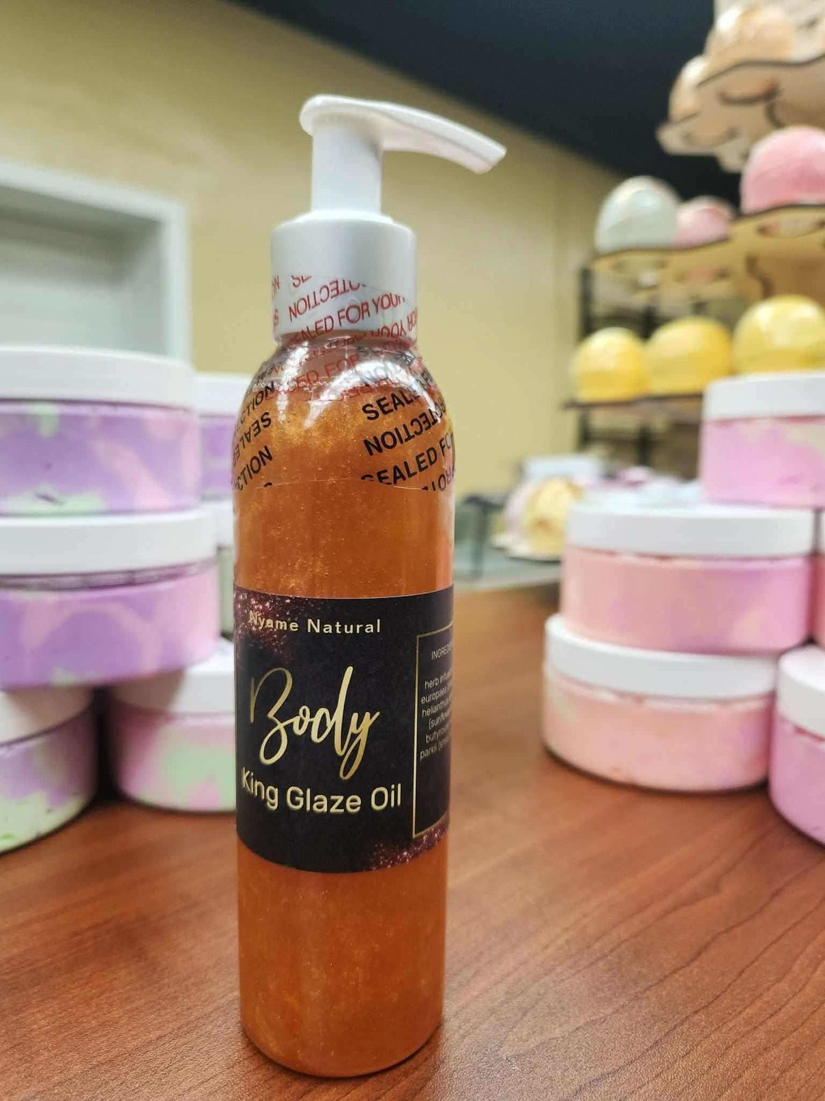 RoyalLuxsLLC natural body oil for men bottle with pump on wooden surface and pastel containers in background