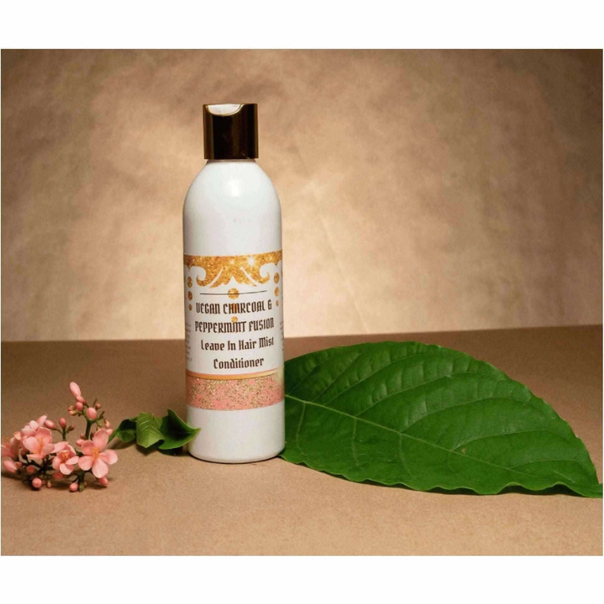 RoyalLuxsLLC vegan leave-in conditioner bottle with charcoal and peppermint next to green leaf and flowers