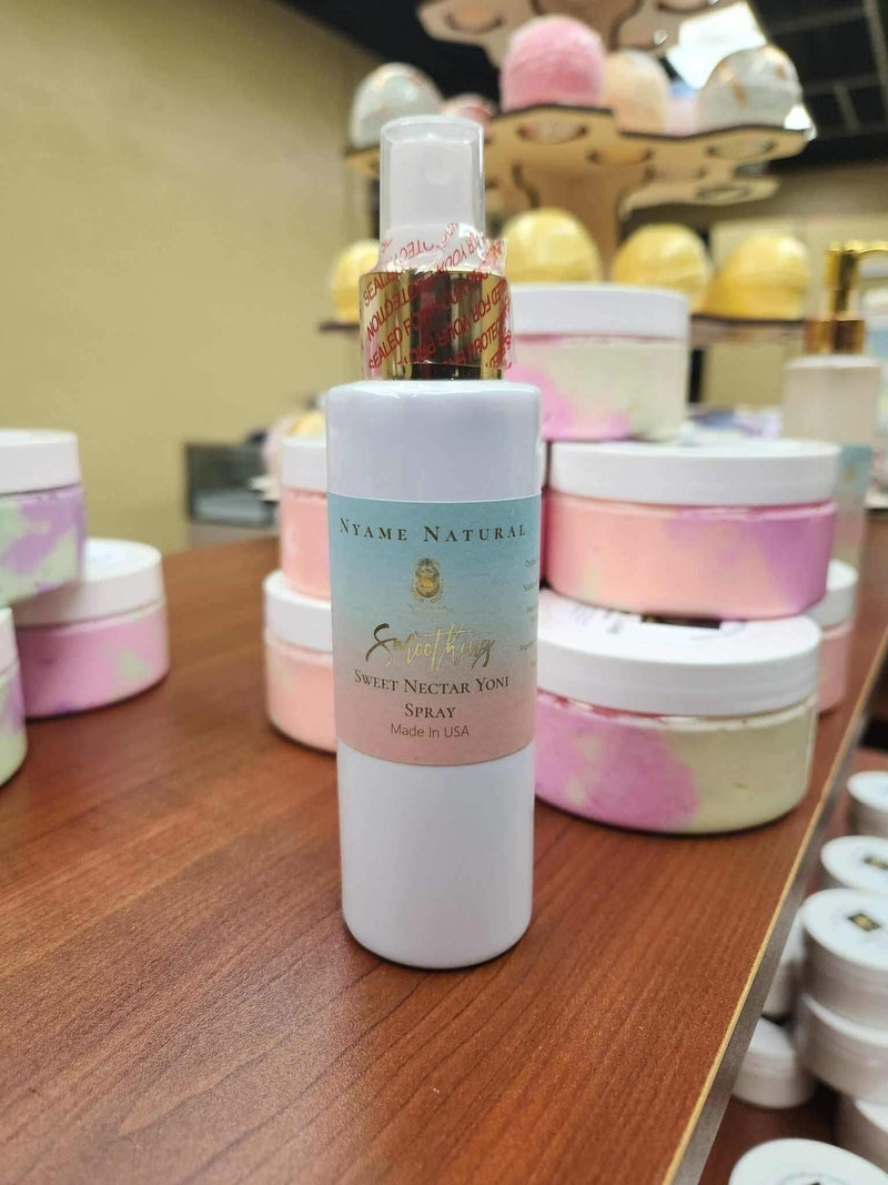 Sweet Yoni Spray Small by Nyame Natural on a wooden display with colorful jars in the background.