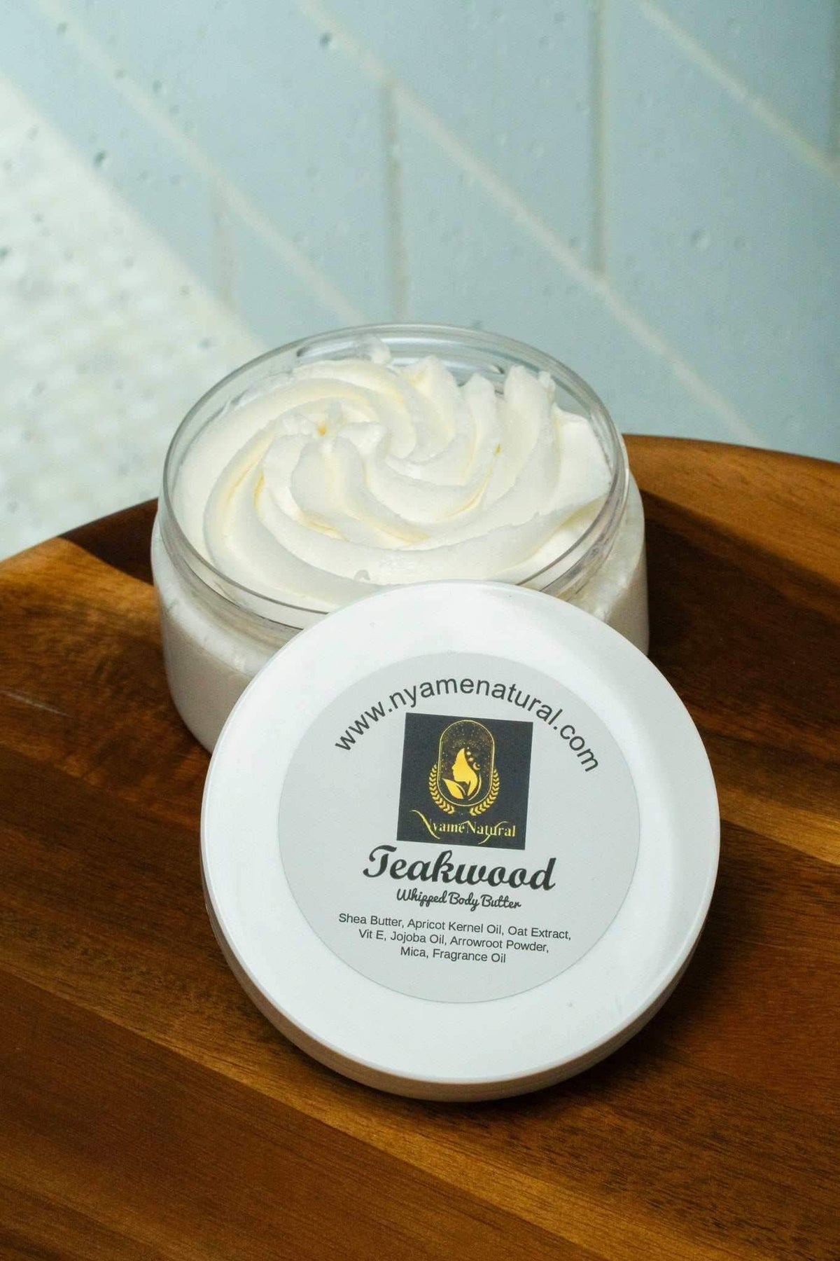 Teakwood Body Butter in a jar with a swirl top on a wooden surface, promoting skin nourishment and hydration.