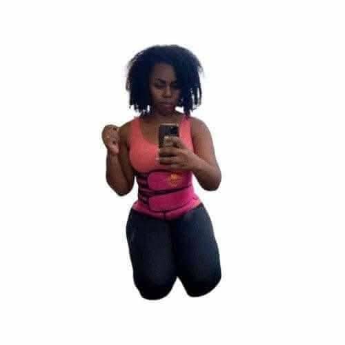 Woman wearing a pink waist trainer for weight loss with black workout leggings taking a mirror selfie